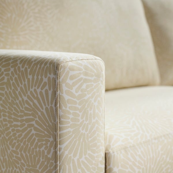 Close-up af en stilfuld sofa med indviklet hvidt og guldmønstret polstring, der fremhæver kvalitetsdesign og komfort.