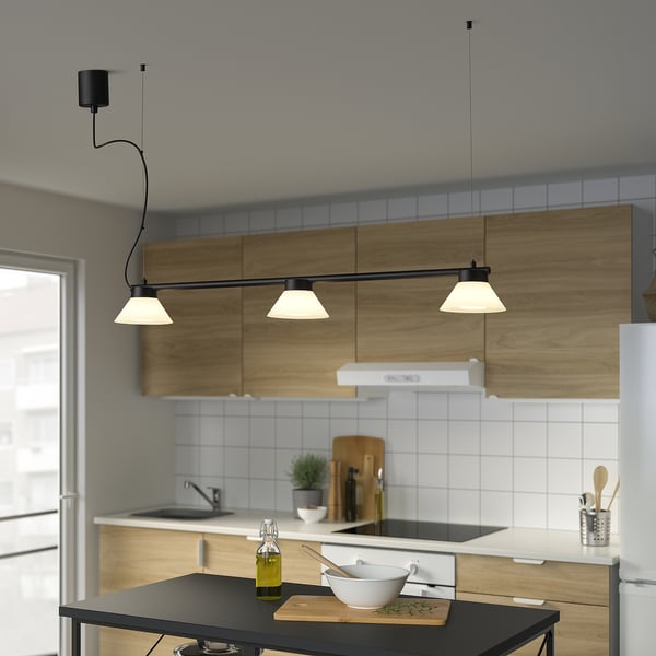 Moderne køkken med SAMBORD sort pendel over øen. Lampen har tre kegler. Hvid bagplade, træskabe og olivenolie på disken.