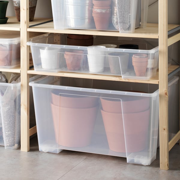 Opbevaringsbeholdere af plast med hjul, der holder lyserøde plantekasser, den største skraldespand har to store.