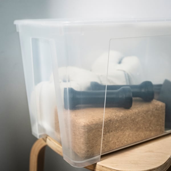 Gennemsigtig plastikopbevaringsbeholder med svampe og blå håndvægte, der viser holdbarhed og gennemsigtighed.