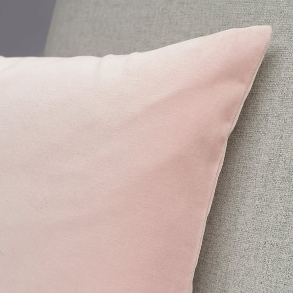Et plys, pastelrosa pudebetræk, der ligger på en sofa. Stoffet fremstår blødt og af høj kvalitet.