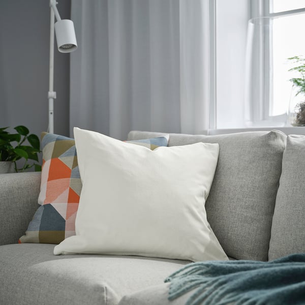 Moderne stue med hvid pude på grå sofa, farverige puder, nær vindue.