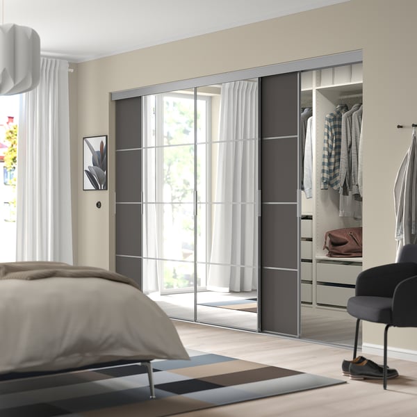 Moderne soveværelse med SKYTTA-garderobe , spejle, neutrale farver, lille sort stol og tæppe.