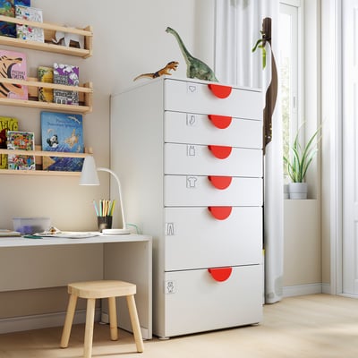 Børneværelse med SMÅSTAD kiste, dinosaurlegetøj, bøger, skrivebord, lampe, plante.