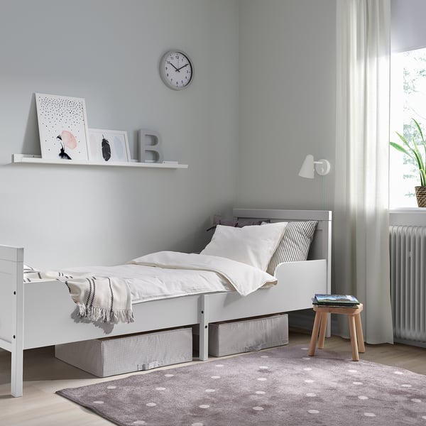 SUNDVIK børneseng, hvid, enkelt design. Grå vægge, ur, opbevaring, skammel, tæppe, lampe, radiator.
