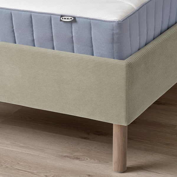 En moderne sengeramme med polstret hovedgærde og træben, designet til komfort og nem rengøring.