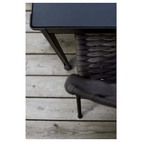 Sort moderne udendørs bord med metalliske ben på en træterrasse.