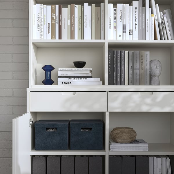 Hvid bogreol med grå opbevaringskasser og pyntegenstande med et rent design.