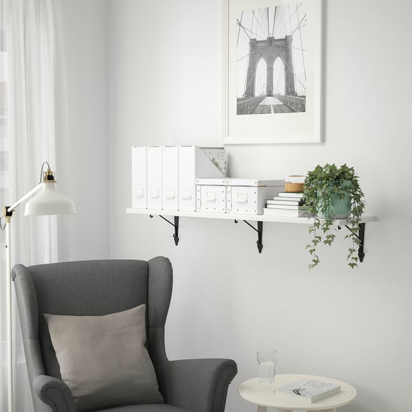 Hyggekrog med TRANHULT hylde, bøger, plante og lænestol. Brooklyn broprint ovenfor, minimalistisk indretning.