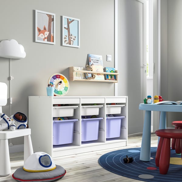 Legerum med hvid TROFAST opbevaringsenhed, lilla skraldespande, bøger, farverig vægkunst, legetøjsbord og astronautlegetøj.
