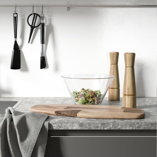 Køkkenbord med salatskål, salt- og peberkværne, ophængningsredskaber og håndklæde.
