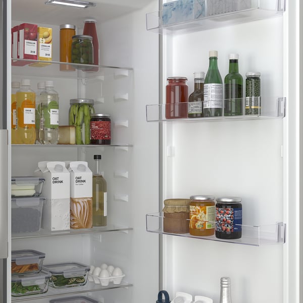 Velorganiseret køleskab med flere hylder og rum, der viser madvarer som flasker, krukker og råvarer, hvilket indikerer effektiv opbevaring.