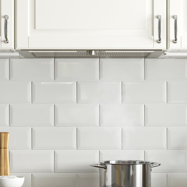 Moderne køkken med hvide skabe, sølvgreb og rustfri kogeplade. Skjult emhætte med led-belysning og fedtfilter.