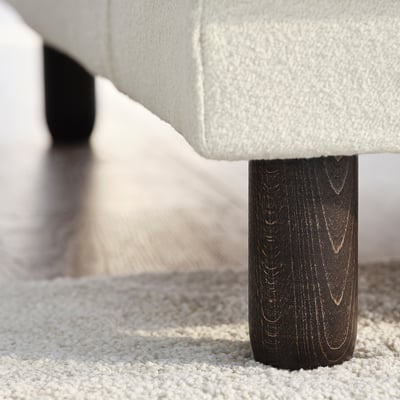 Nærbillede af UPPÅKRA-sofaens ben, der viser mørkt træfinish og robust håndværk.