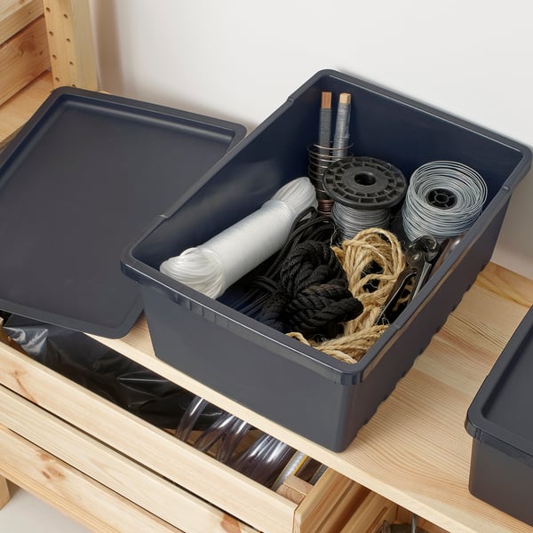 Opbevaringsbeholder af plast med låg indeholdende spoler af reb og tråd, der sidder på en træhylde.