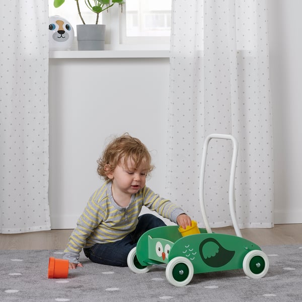 Barn, der leger med UPPSTÅ rollator, lærer at balancere og gå. Dette støttende legetøj har justerbare hjul og et grønt ugledesign.
