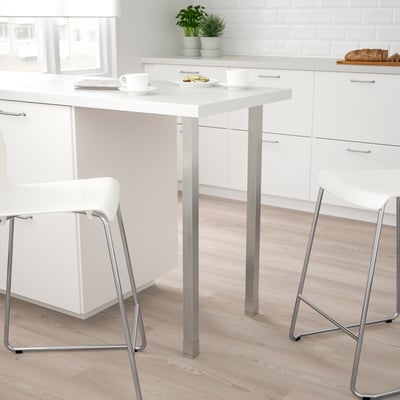 Moderne køkken med hvide UTBY bord og stole, små, metalliske ben, enkelt design, sat mod hvide skabe.