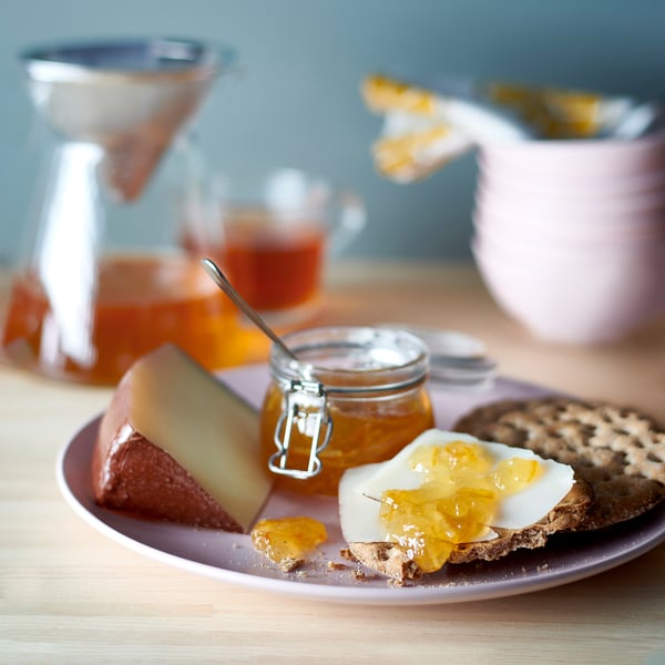 Et fad med brød, ost, appelsinmarmelade og en kande. VAGGSÅNG appelsin- og hyldeblomstpålæg.