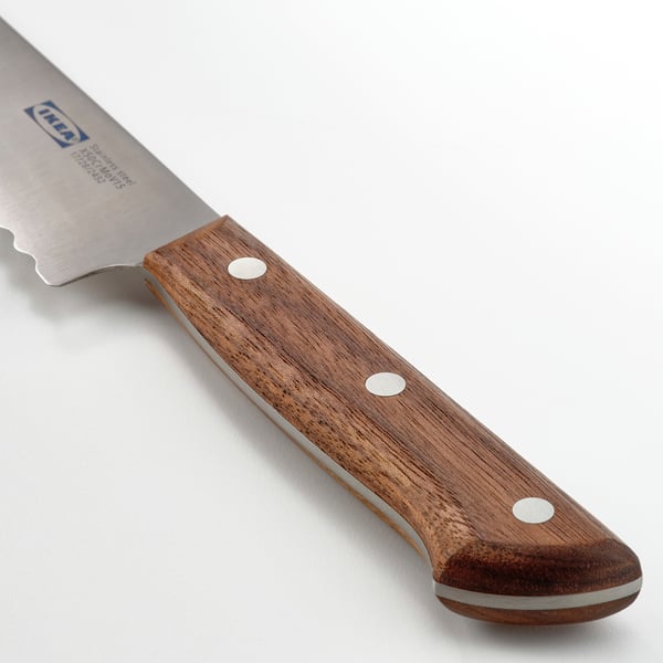 Kniv med savtakket blad og mørkt valnøddehåndtag, der viser skarp og afbalanceret kvalitet.