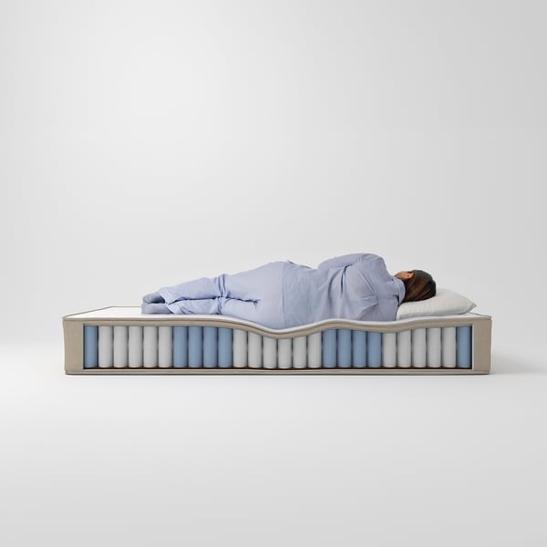 Person, der sover på blå madras, der viser sin komfort, skiftende fasthedszoner for nakke, ryg og skuldre.