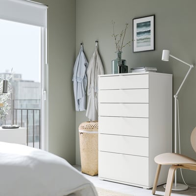 Moderne soveværelse med hvid VIHALS kommode, lysegrønne vægge, træstol, lampe, tekstiler og naturprint.