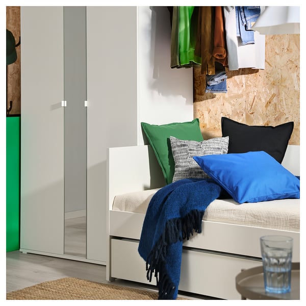 Moderne hvid daybed med blåt tæppe, puder, ved siden af garderobe.