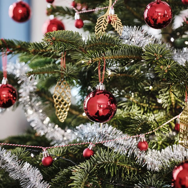 Juletræ med røde og gyldne ornamenter, lyst glimmer og lys.