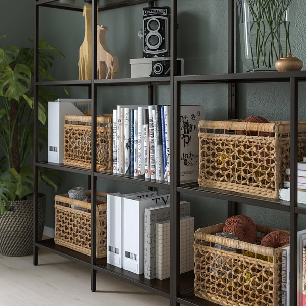 Sorte metalhylder med glas, der viser bøger, dekorative kurve og girafskulpturer.