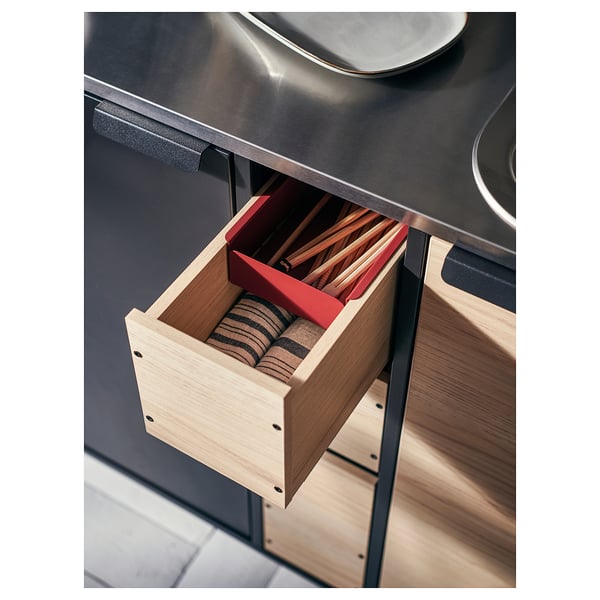Open kitchen drawer in black unit with wooden divider holding cutlery.