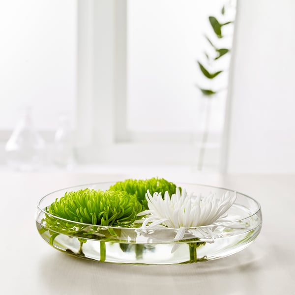 Clear glass bowl displays green and white flowers, arranged for decoration.