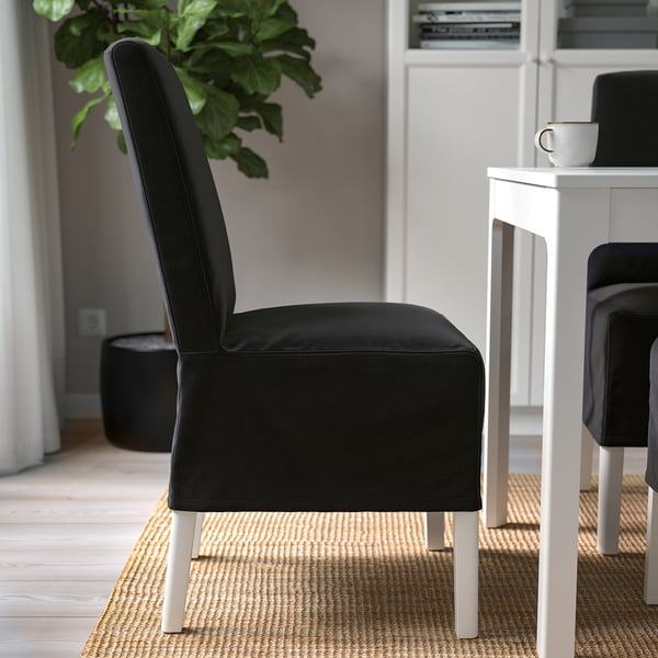 Black upholstered chair with wooden legs near a white dining table on a woven rug, showcasing its comfortable and stylish design.