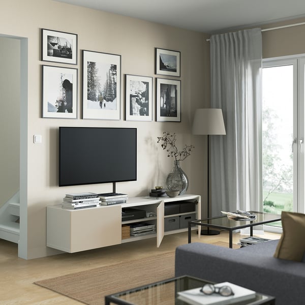 Modern living room with BESTÅ tv bench, shelves, cable management, and airy design. Flat-screen tv, photos, grey curtains.