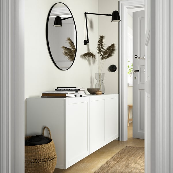 Modern white BESTÅ cabinet with mirror, lamp, basket and plants. Wall-mounted, saves floor space.