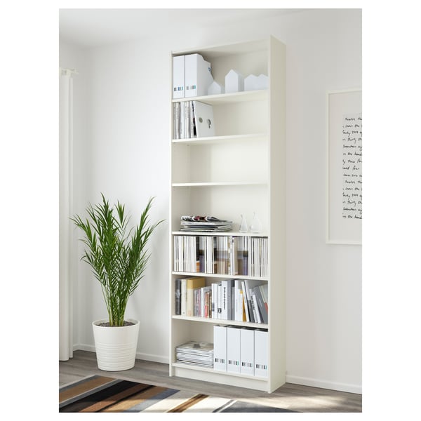 White BILLY bookcase with adjustable shelves, storing books and decor, next to a tall plant.