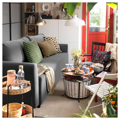 Modern living room with grey BRISSUND sofa, wooden tables, patterned pillows, and cosy decor.