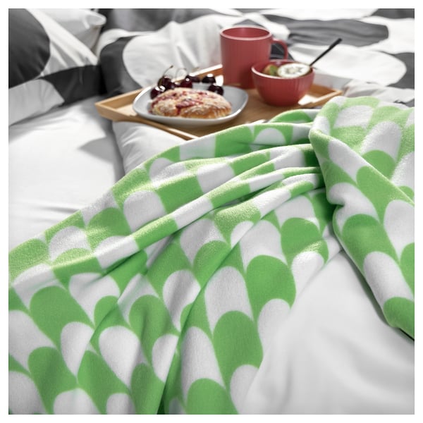 Cosy green and white patterned throw blanket on bed with breakfast tray.