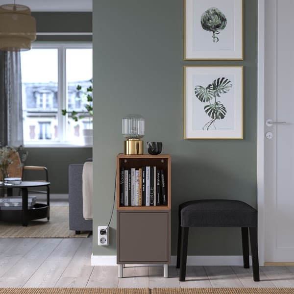 Small wooden bookshelf, black accents, next to a large framed plant print on a green wall.