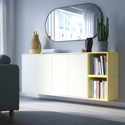 Modern living room with EKET white and light yellow storage unit against wall, mirror above, decorative items, and grey chair.