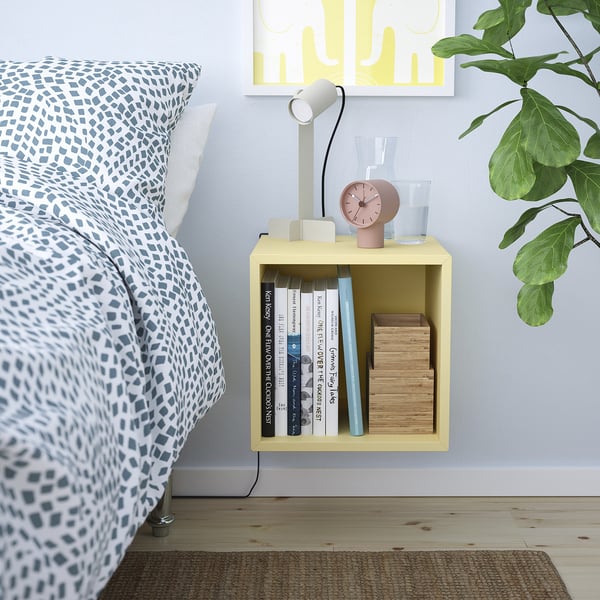 EKET yellow cube shelf by bed. Holds books & decor. Small, bright, modern.
