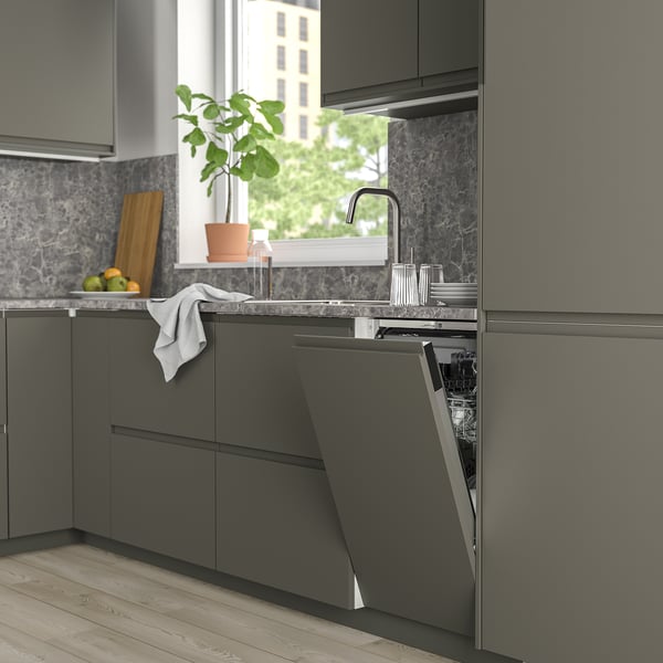 Modern kitchen with sleek FRÖSLUNDA dishwasher, dark cabinets, stainless steel, plant, and fresh produce.