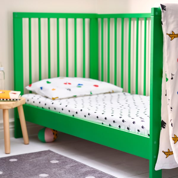 Green GRÖNFINK kids bed with tree-pattern sheet, small wooden stool, and toys. Modern, safe, and playful.