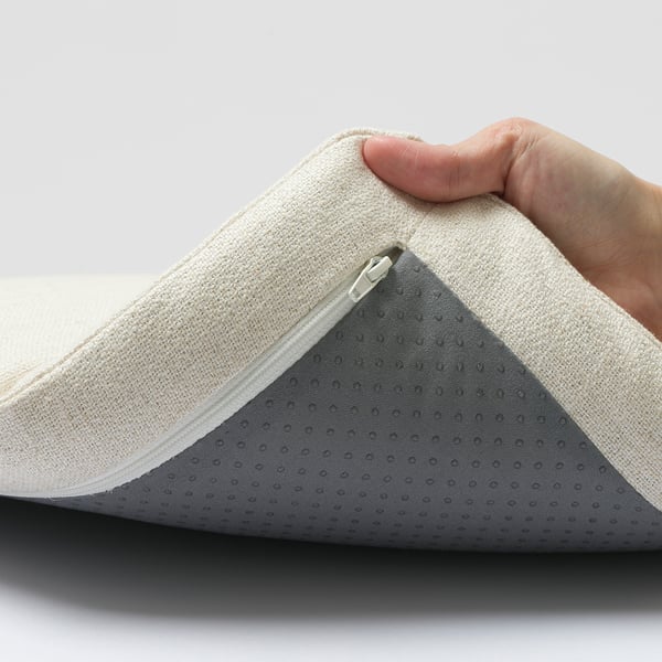 Person holding cushion with zip detail.