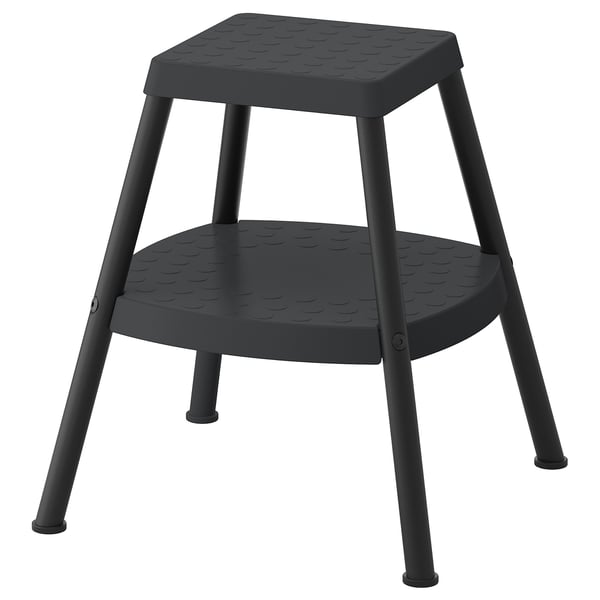 Black step stool with plastic seat and legs, textured surface for grip, square seat, designed for reaching high places.