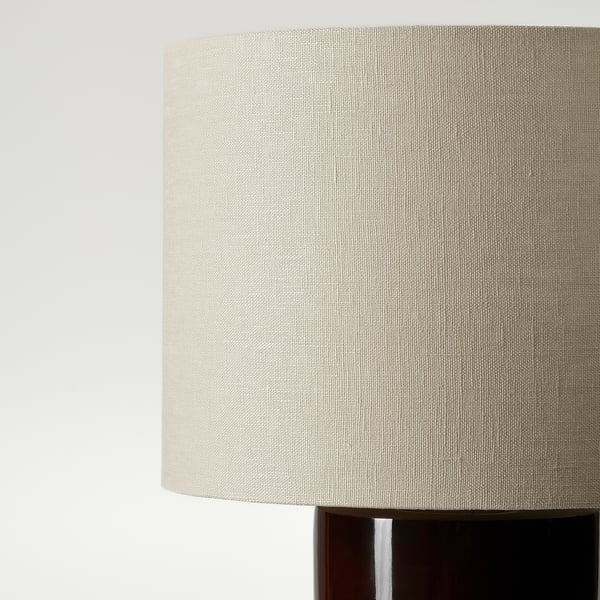 Cylindrical linen lamp shade atop dark base, illustrating soft texture and quality craftsmanship.