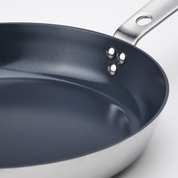 Closeup of a stainless steel frying pans handle and non-stick interior.