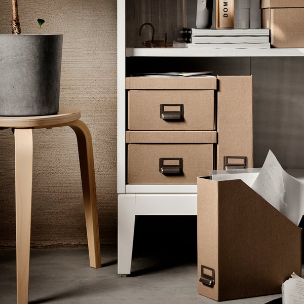 Modern storage unit, IDANÄS series. White shelves with woven beige drawers. Curtains, books, and stool shown.