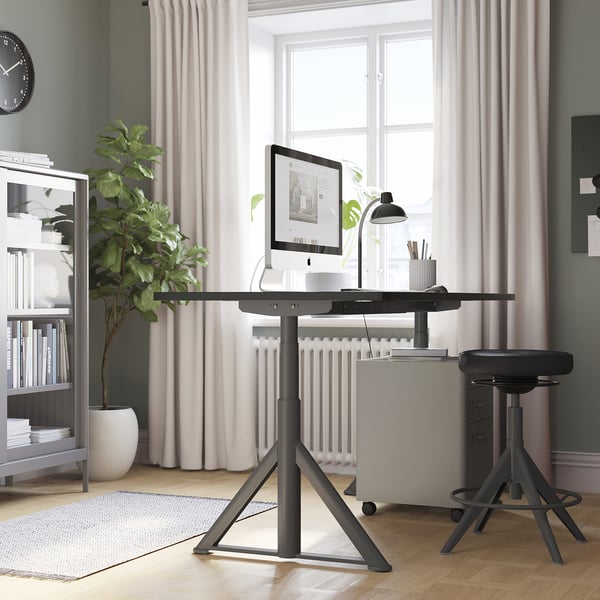 Modern home office with IDÅSEN standing desk, stool, and large window.