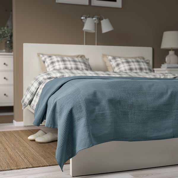 Blue INDIRA recycled cotton bedspread on double bed with white headboard & lamp.
