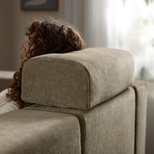 A person relaxes on a comfortable, light grey JÄTTEBO modular sofa, enjoying its supportive cushions and soft fabric.