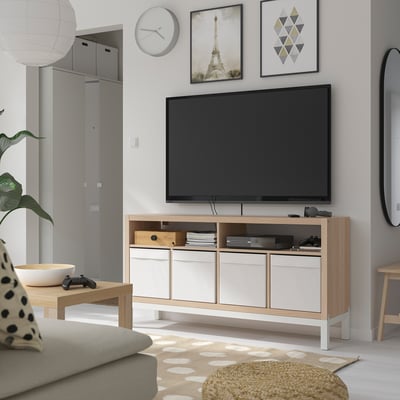 Minimalist tv room with KALLAX tv bench, flat-screen tv, gaming accessories, books, grey sofa, rug, wall art, clock, coffee table, and mirror.